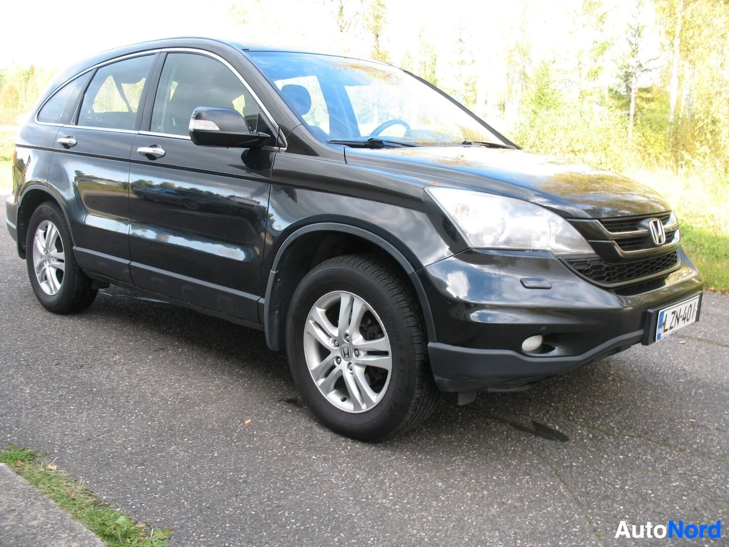 Etuviisto, nokka oikealle: Musta auto kuvattuna etuviistosta vasemmalta puolelta asfaltilla, auton keula osoittaa oikealle. Ajovalot, etusäleikkö ja vasen kylki näkyvät. Rekisterik