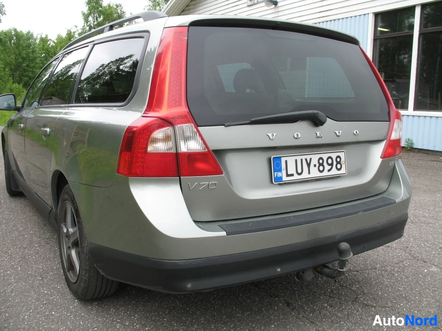 Takaa: Vaaleanvihreän Volvo V70 -farmariauton takaosa parkkipaikalla. Autossa on vetokoukku. Rekisterikilpi on