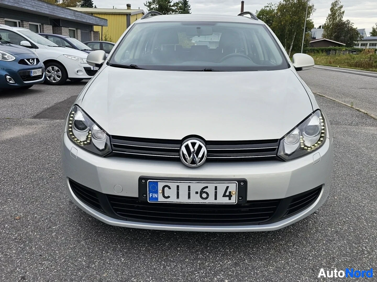 Edestä: Hopeanvärinen farmariauto edestä päin kuvattuna. Rekisterikilpi näkyy selvästi.