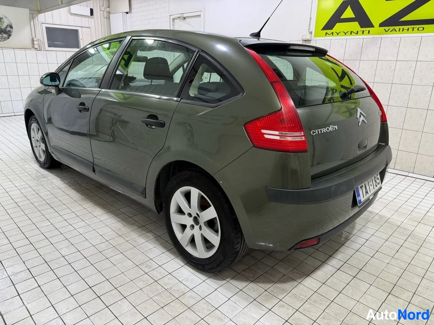 Takaviisto: Vihreä henkilöauto kuvattuna takaa ja vasemmalta puolelta. Takaluukussa lukee "CITROËN" ja "C4". Autossa on valkoiset kevytmetallivanteet. Rekisterikilpi "" näk