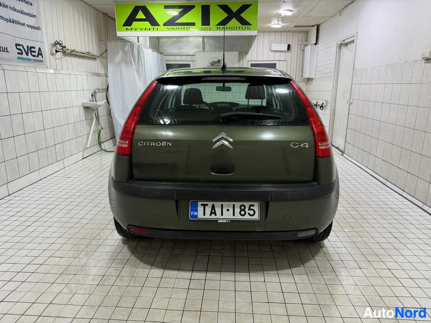 Takaa: Vihreän henkilöauton takaosa, jossa takaluukussa lukee "CITROËN" ja "C4". Takalasinpyyhin on näkyvissä. Rekisterikilpi on "".