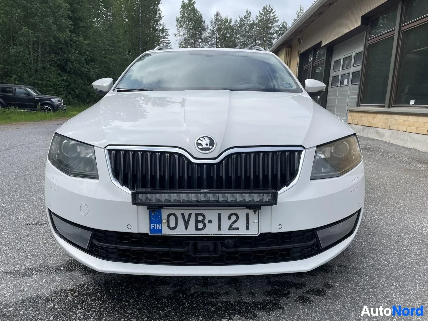 Edestä: Auton etuosa kuvattuna suoraan edestä. Autossa on musta etusäleikkö ja etupuskurissa on kiinnitettynä LED-lisävalopaneeli. Rekisterikilpi "" on näkyvissä.