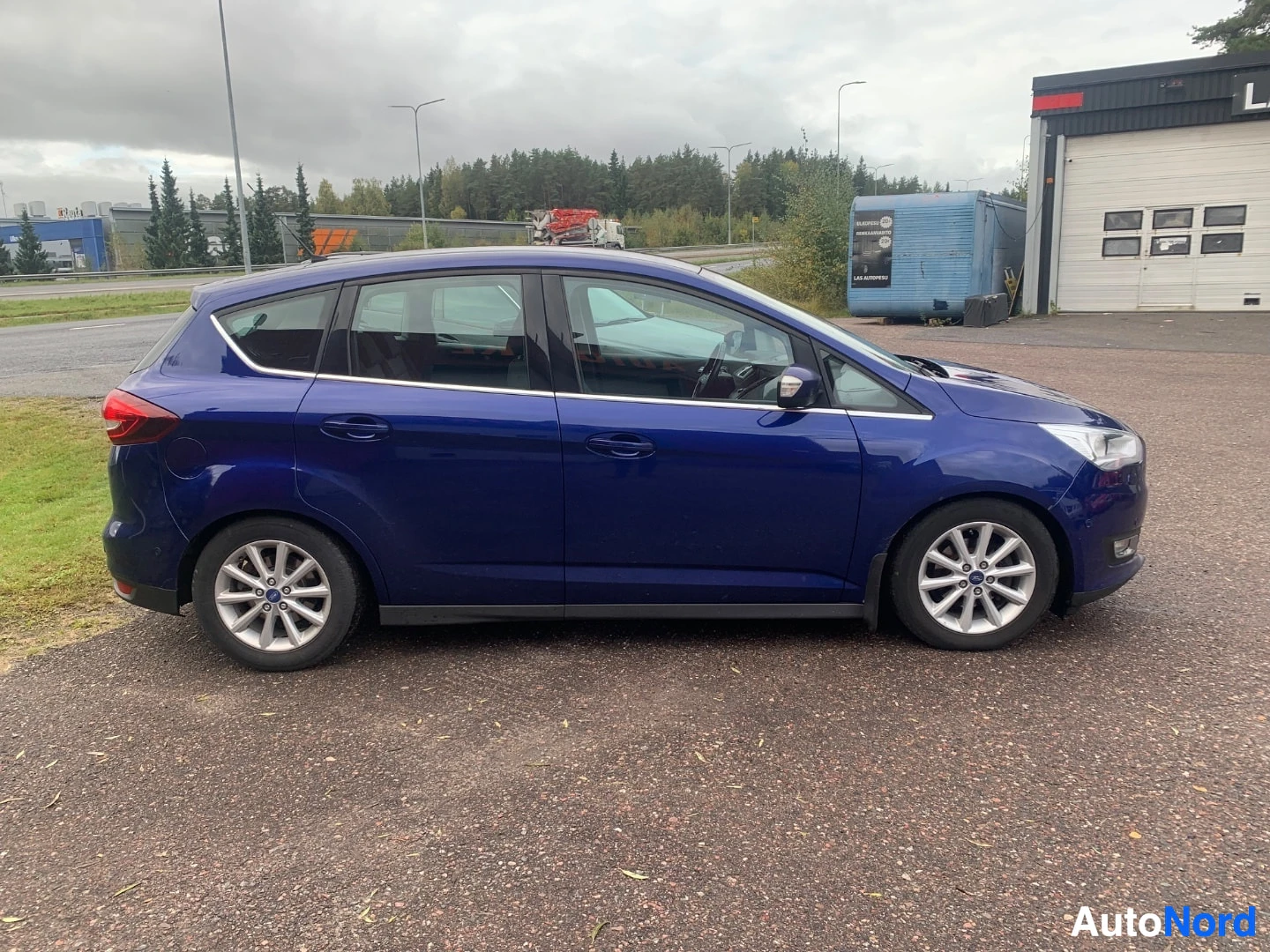 Etuviisto, nokka oikealle: Sininen farmarimallinen henkilöauto sivulta kuvattuna, kevytmetallivanteet ja kattokaiteet näkyvät.