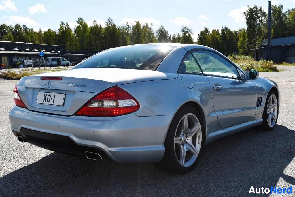 Takaviisto: Hopeanvärinen Mercedes-Benz SL -urheiluauto takaa oikealta kuvattuna, kova laskettu katto ylhäällä.