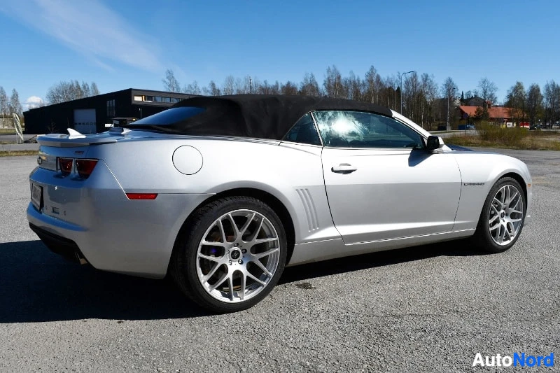 Takaviisto: Hopeanharmaa avokori Chevrolet Camaro takaa oikealta laidasta, musta kangaskatto, hopeat monisakaraiset vanteet ja auringonpaiste takaikkunassa.