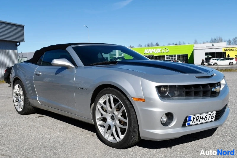 Etuviisto, nokka oikealle: Hopeanharmaa Chevrolet Camaro -avolava kulmassa edestä vasemmalta, musta katonauha, kevytmetallivanteet ja rekisterikilpi.