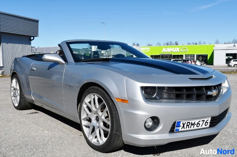 Etuviisto, nokka oikealle: Hopeanharmaa avo-Chevrolet Camaro edestä kolmannelta vasemmalle; tumma konepelti, hopeavanteet, rekisterikilpi.