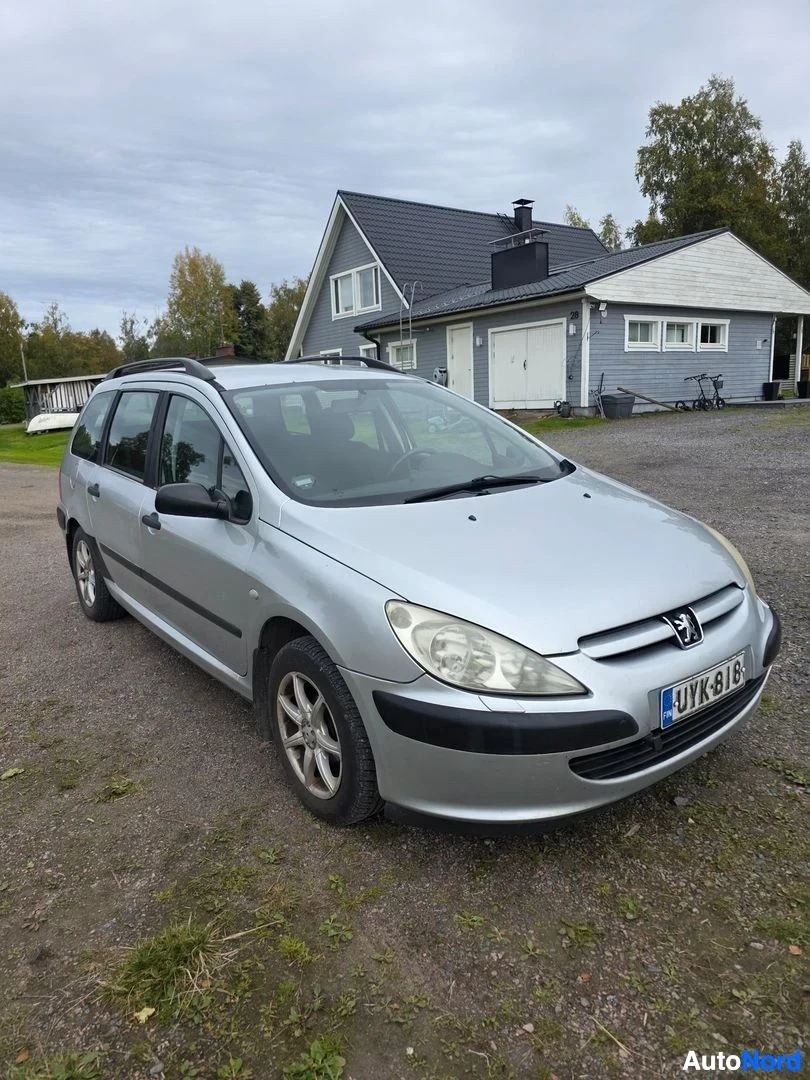 Etuviisto, nokka oikealle: Hopeanvärinen farmariauto kuvattu etukulmasta oikealta, rekisterikilpi.