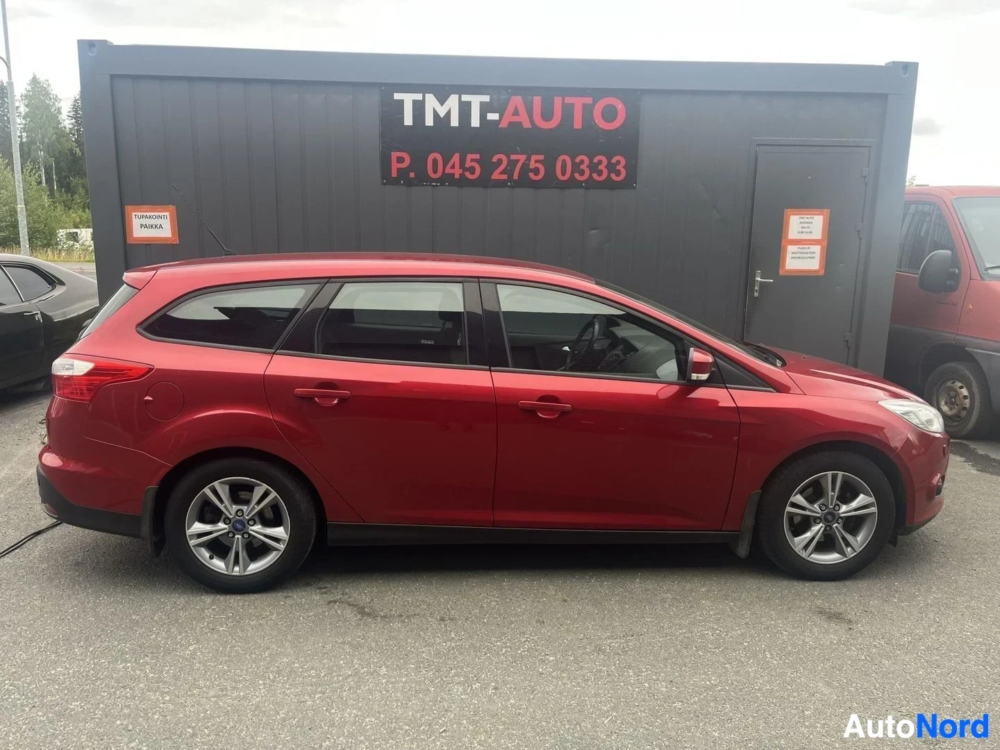 Sivulta: Punaisen Ford Focus -farmarin sivukuva koko auton sivulta, nokka kuvan oikealla.