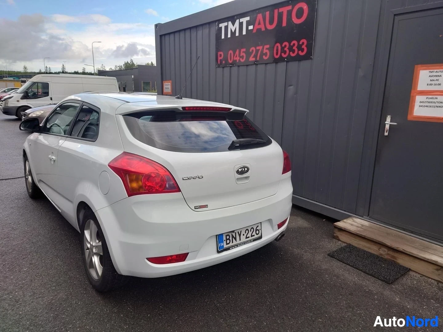 Takaviisto: Valkoinen Kia Cee'd auto TMT-Auto -rakennuksen edessä takaa nähtynä.
