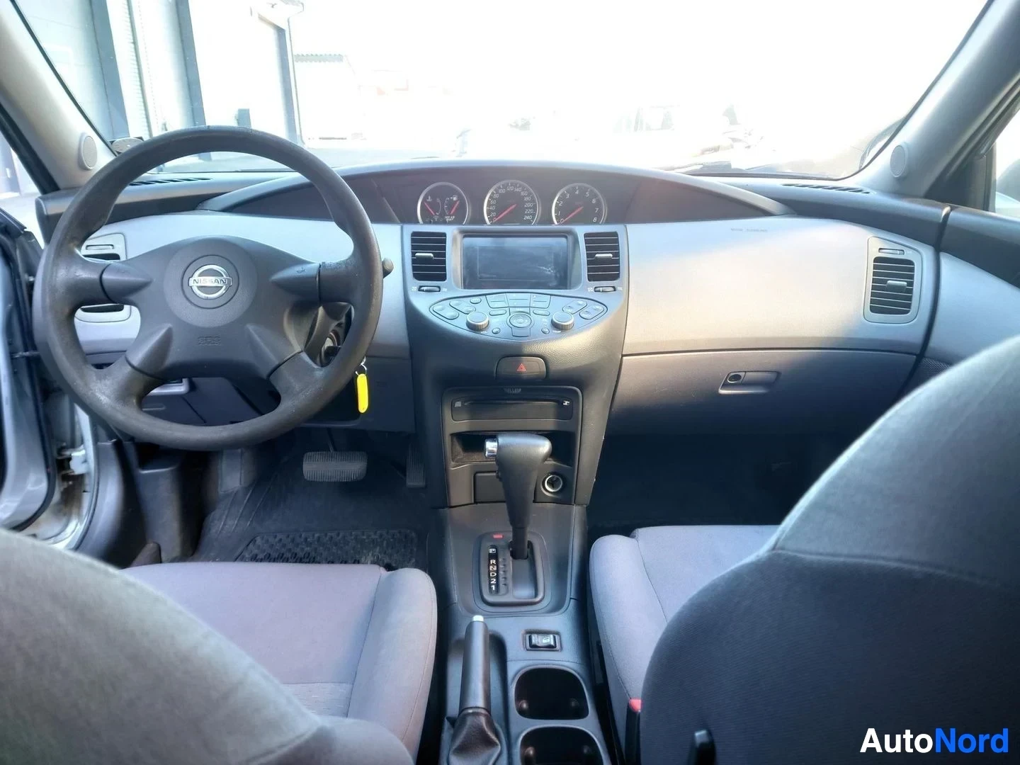 Ohjaamo: Ohjaamo vasemmalta katsottuna: Nissan-ohjauspyörä, mittaristo ja keskikonsolin automaattivaihteiston valitsin