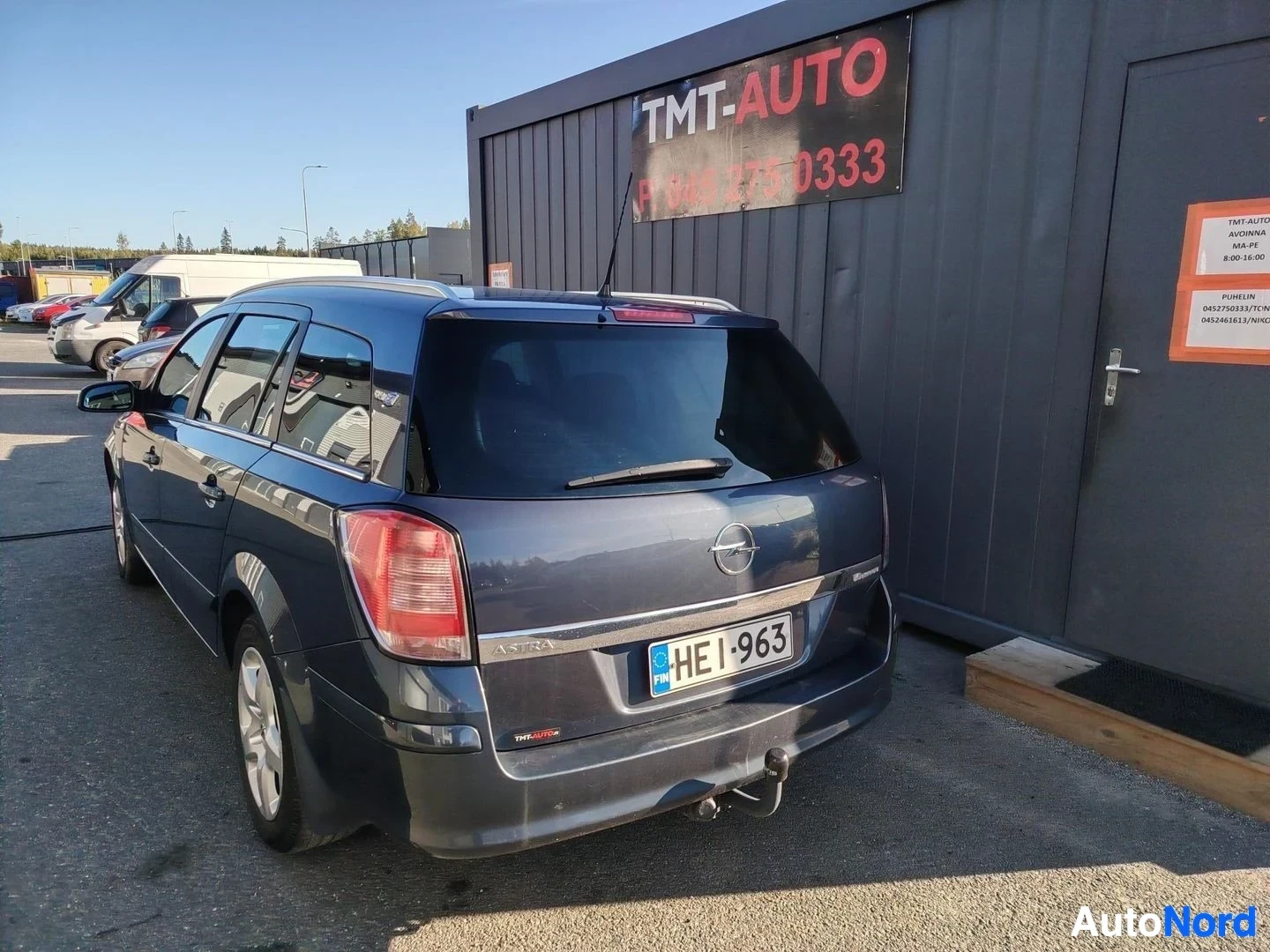 Takaviisto: Tummansininen farmariauto takakulmasta, rekisterikilpi ja vetokoukku näkyvissä.
