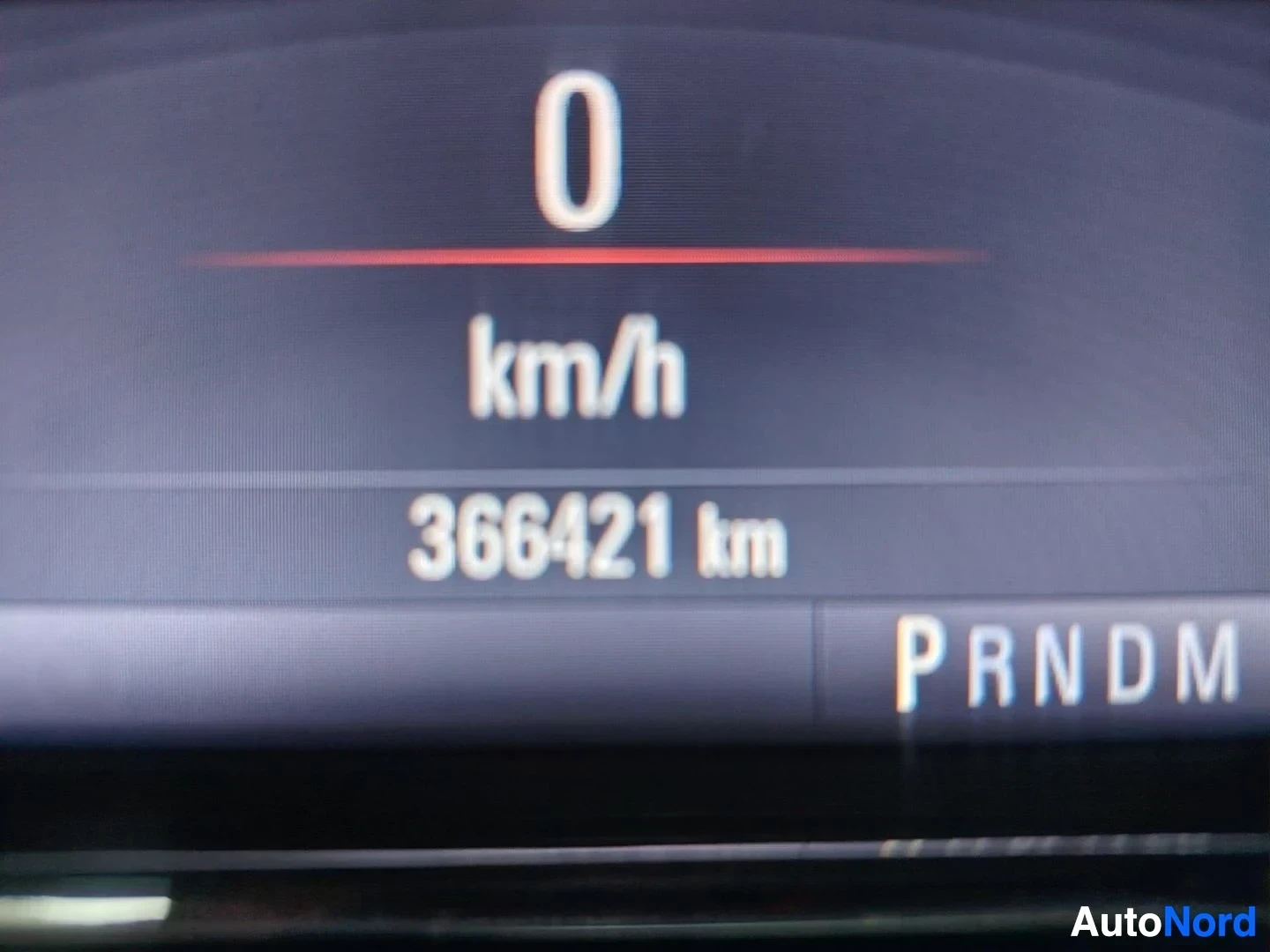 Yksityiskohta: Koenäytön lähikuva: nopeus 0 km/h, matkamittari 366421 km ja vaihteiston P R N D M -merkinnät.