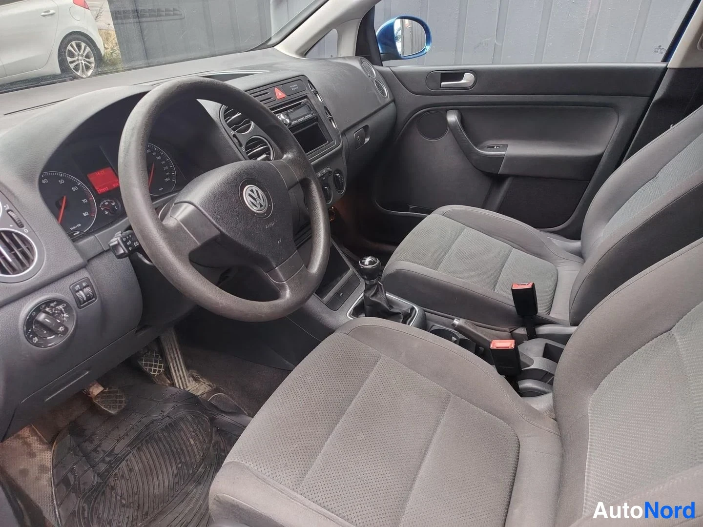 Muu: Auton etuistuin ja ohjaamo: Volkswagen-ohjauspyörä, mittaristo, manuaalivaihteisto ja harmaat istuimet.