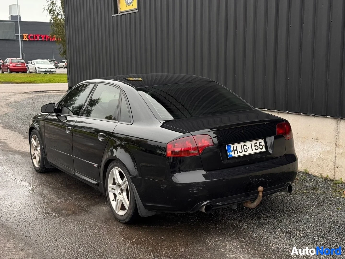 Takaviisto: Mustan Audi A4 -sedanin takakulmakuva vasemmalta; rekisterikilpi, perävaunukoulu ja kaksoispakoputki näkyvät.