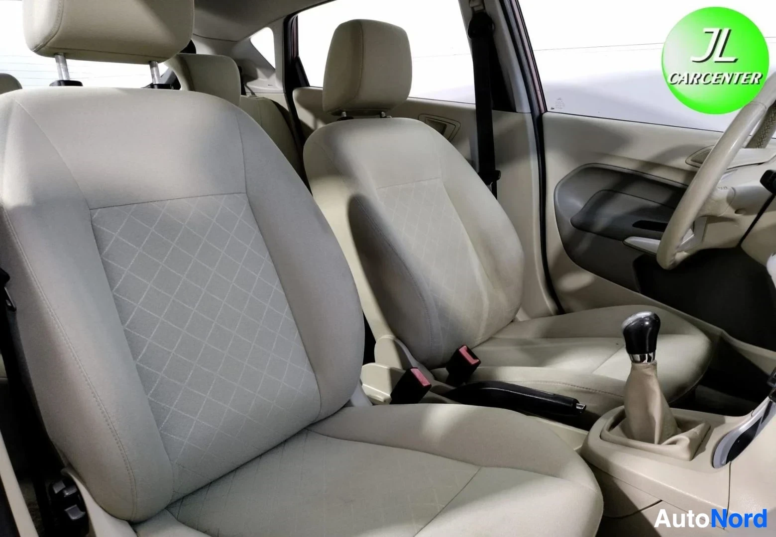Muu: Ford Fiesta -etupenkit beigena kangasverhoiltuna, takana manuaalivaihteen keila ja käsijarru.