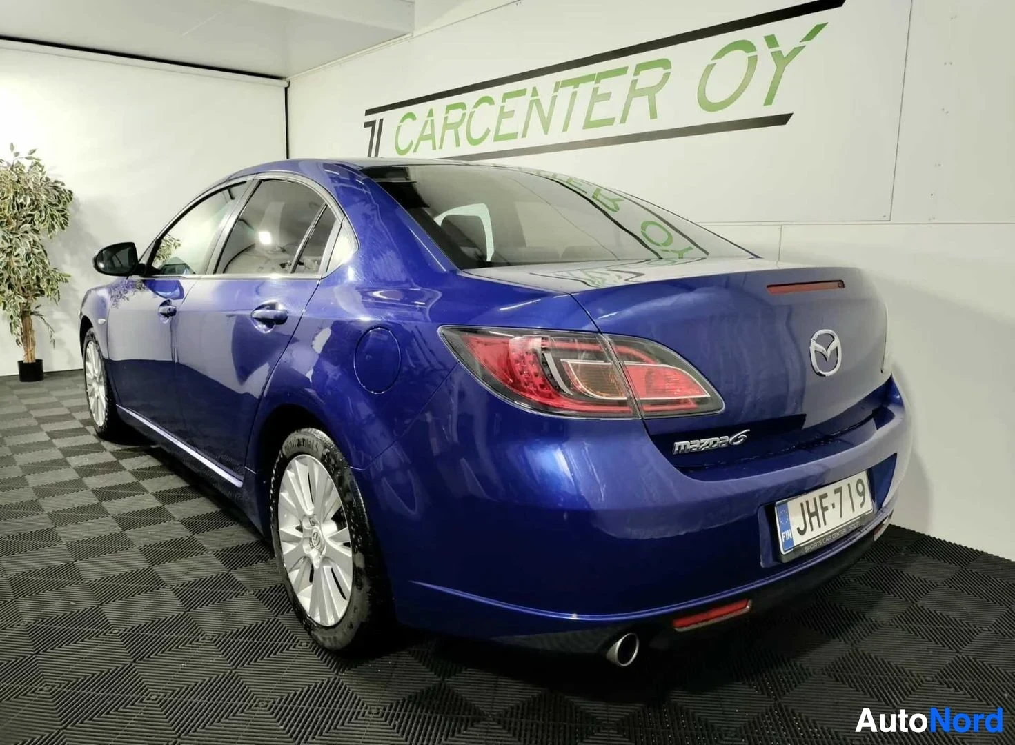 Takaviisto: Sininen Mazda 6 -sedan kulmakuva takaa oikealta, Mazda 6 -merkintä takaluukussa ja rekisterikilpi.