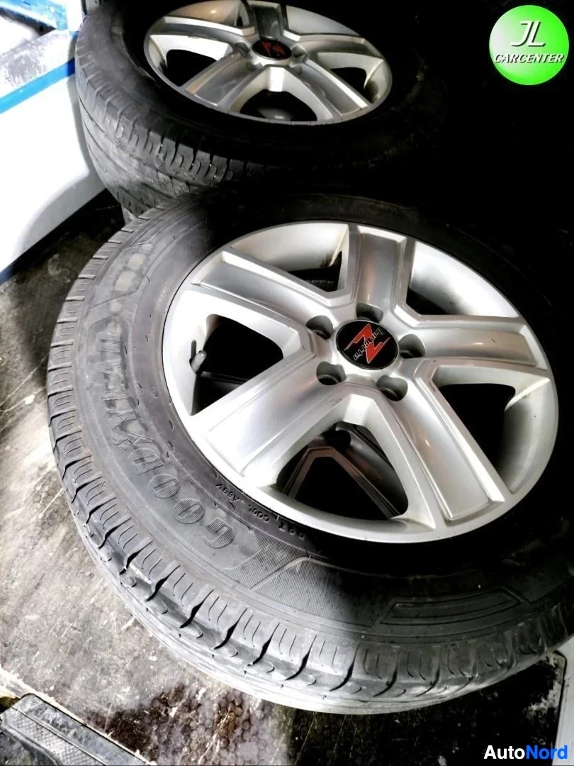 Yksityiskohta: Kaksi metallic-väristä alumiinivannetta renkailla lattialla, nokka-logo keskiöissä.