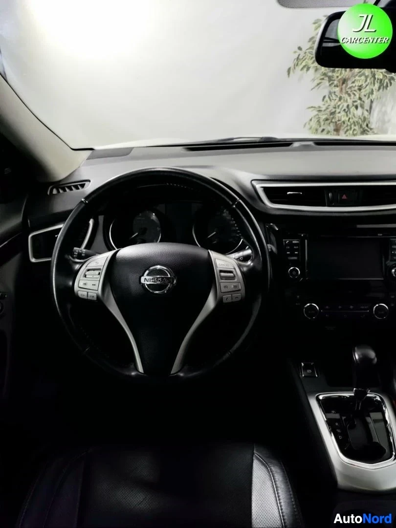 Muu: Ohjauspyörä ja kojetaulu lähikuvassa, Nissan-merkki näkyvissä, vaihteenvalitsin osittain oikealla.