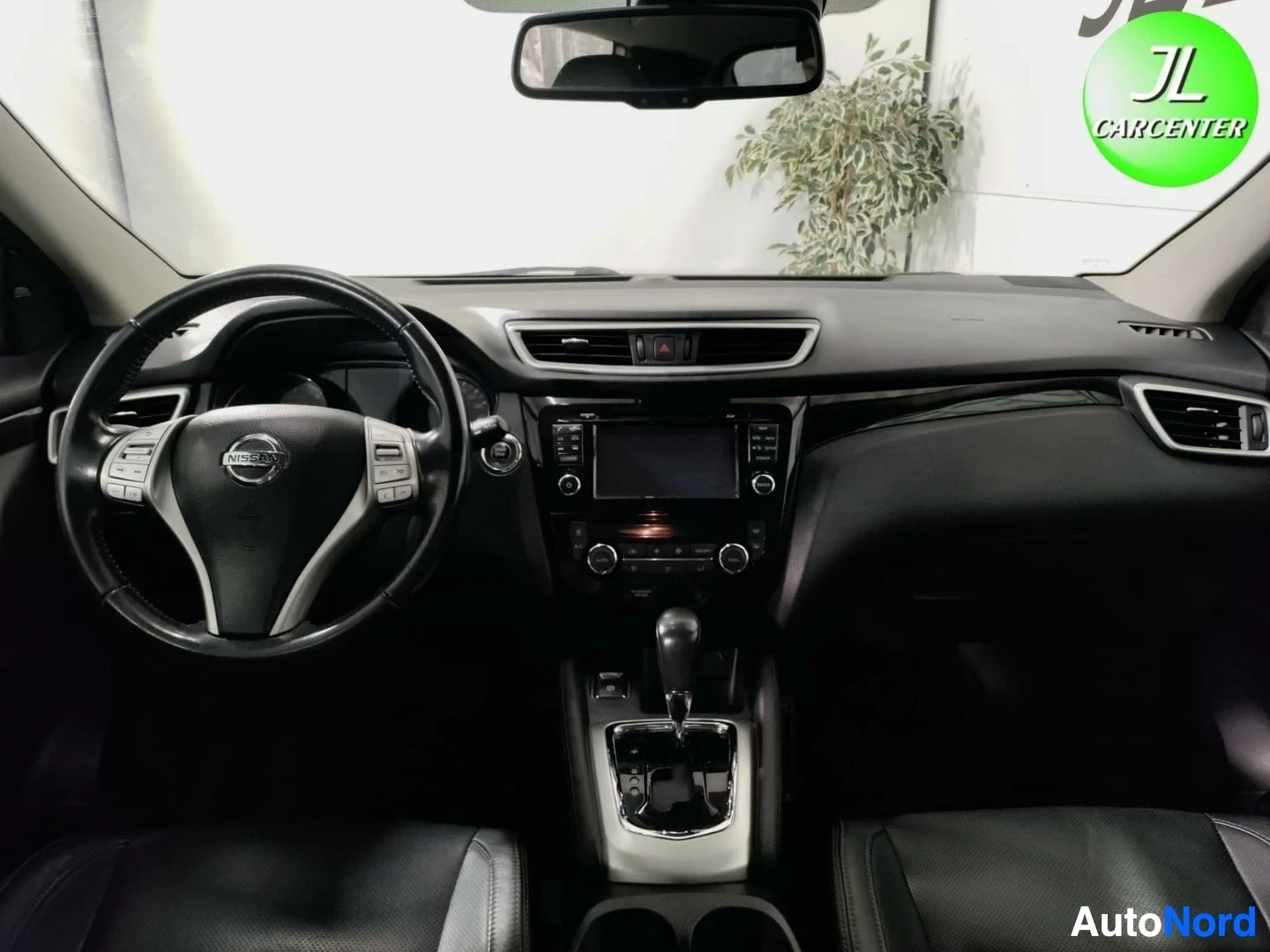 Muu: Ohjaamo etupuolelta: Nissan-ohjauspyörä, kojelauta, keskinäytön multimedialaite ja automaattivaihteiston valitsin.