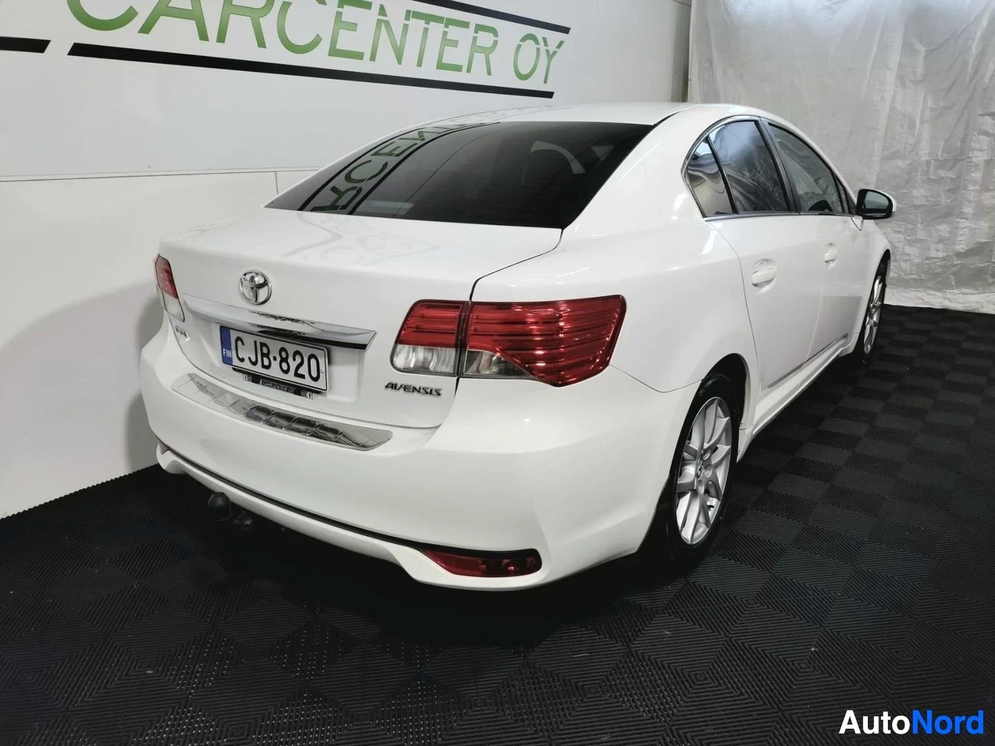Takaviisto: Toyota Avensisin takapää ja oikea kylki valkoisena, rekisteri, Avensis-kylkiteksti näkyvissä.