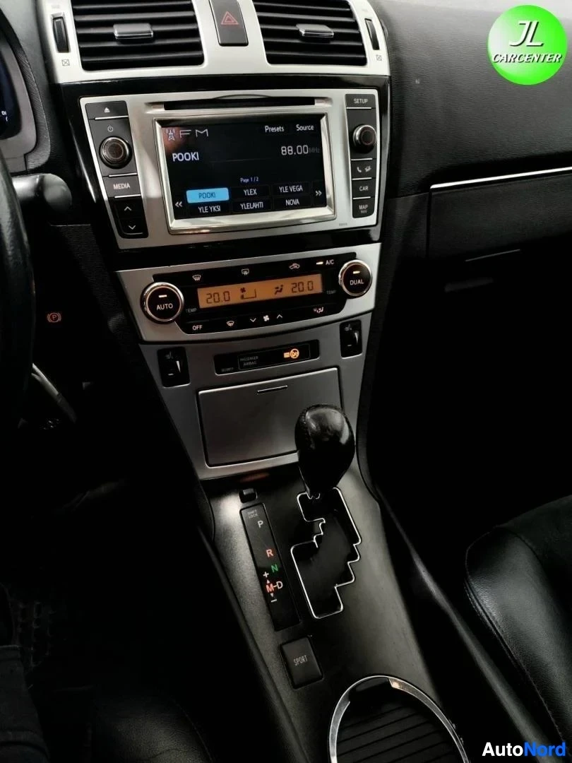 Muu: Keskikonsoli lähikuvassa: radio näyttää tekstiä POOKI 89.00, automaattivaihteen valitsin ja sen vieressä lukema 20.0.