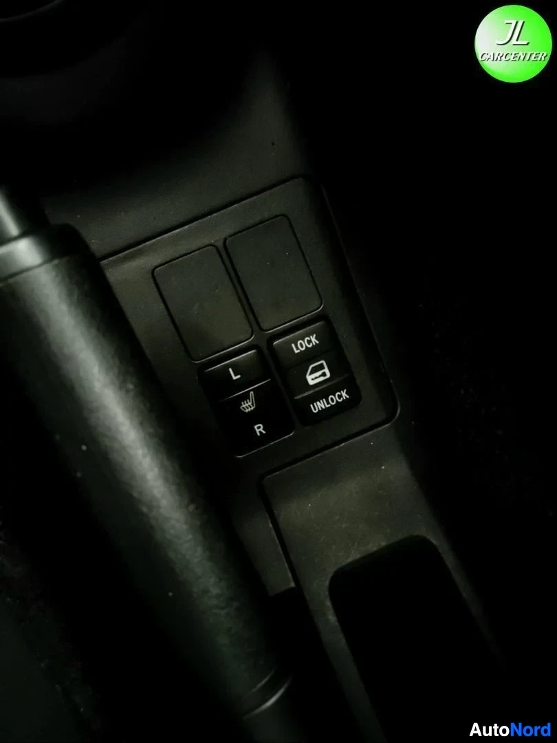 Muu: Pimeä sisätilakuvan lähikuva oven säätimistä, teksti LOCK/UNLOCK sekä L ja R näkyvät himmeästi.