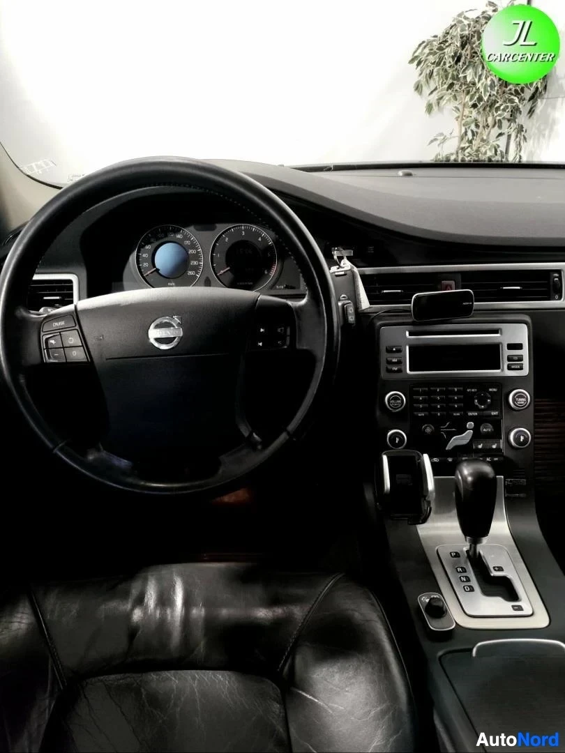 Ohjaamo: Volvo-ohjauspyörä, mittaristo, keskikonsoli ja automaattivaihteen valitsin, mustat nahkaistuimet.