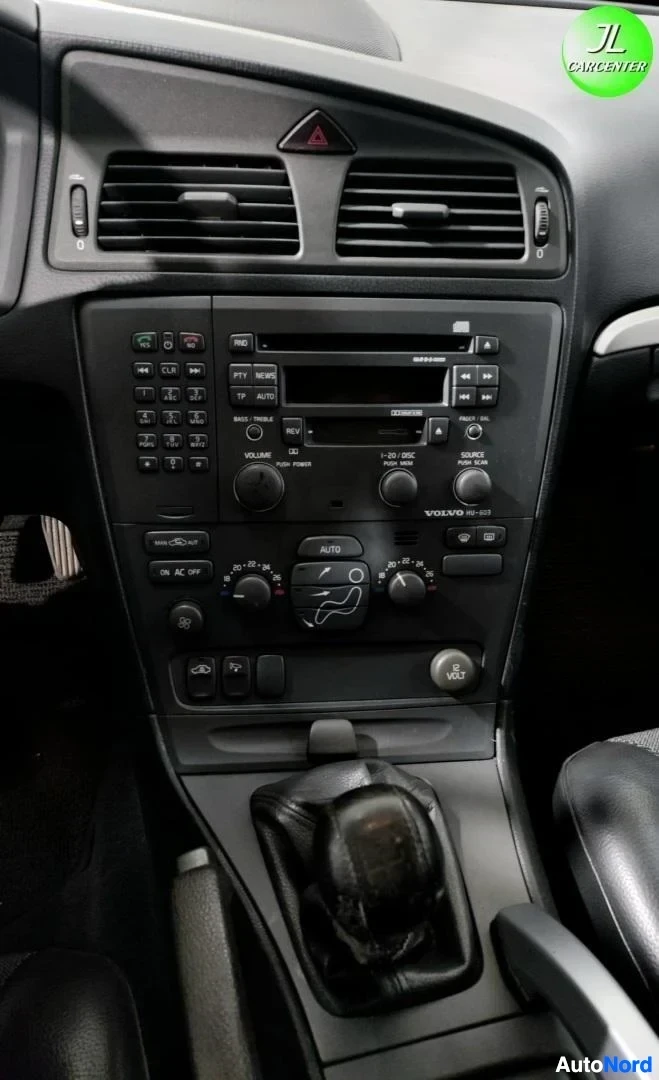 Yksityiskohta: Keskiöpaneelin lähikuva: radio, ilmastointisäätimet ja vaihteenvalitsin, teksti VOLVO HU-603