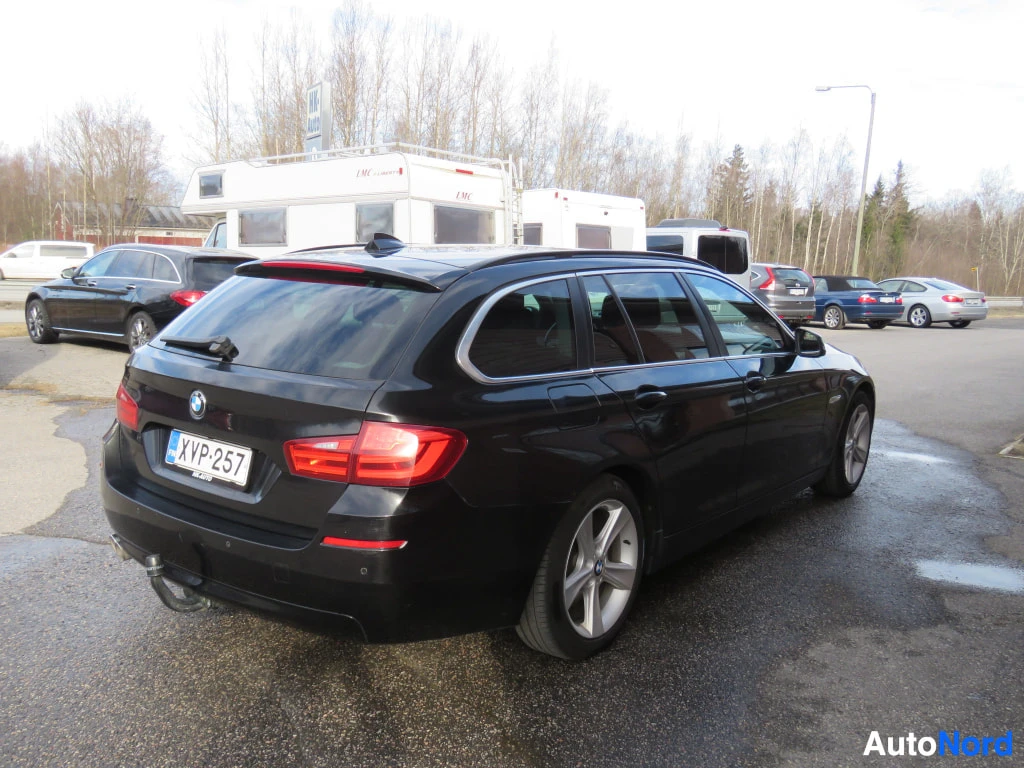 Takaviisto: Musta BMW 5-sarjan farmari takaa viistosti, rekisteri, takana vetokoukku, hopeavanteet.