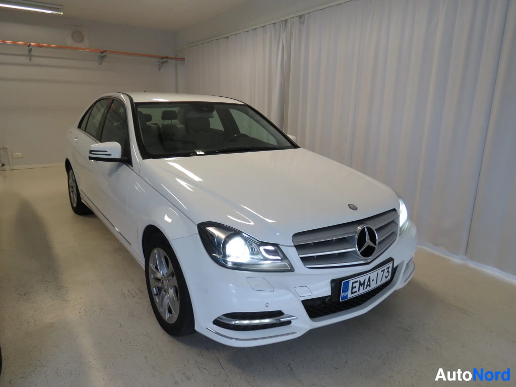Etuviisto, nokka oikealle: Valkoinen Mercedes-Benz C-sarjan sedan edestä vinosti kuvattuna, säleikkö ja ajovalot näkyvissä.