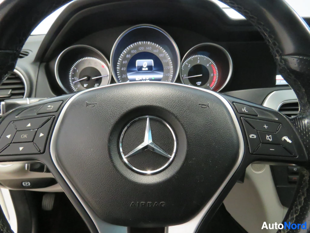 Yksityiskohta: Rattijen Mercedes-Benz-merkki, kojelaudan mittaristo ja ratin monitoimipainikkeet