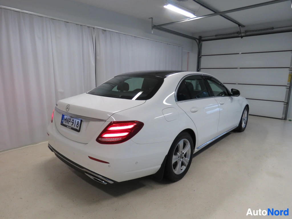 Takaviisto: Mercedes-Benz E-sarjan sedan takaviistosta oikealta, valkoinen kori, rekisterikilpi.