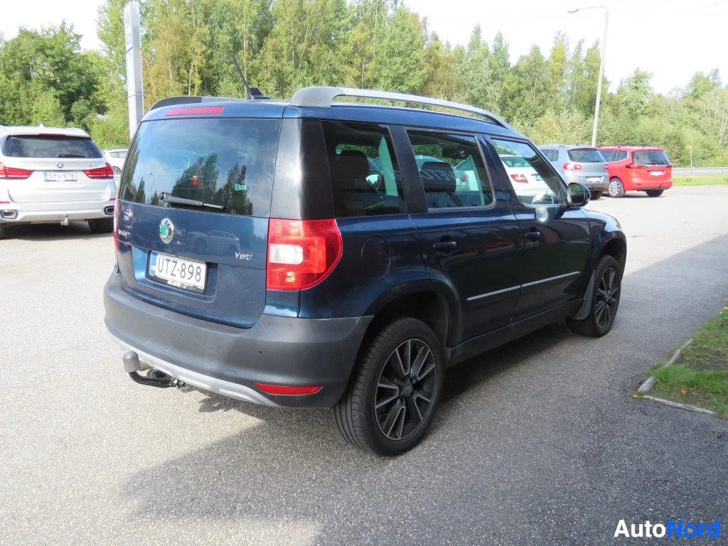 Takaviisto: Sininen Skoda Yeti takakulmasta vasemmalta, rekisterikilpi ja kattokaiteet näkyvät.