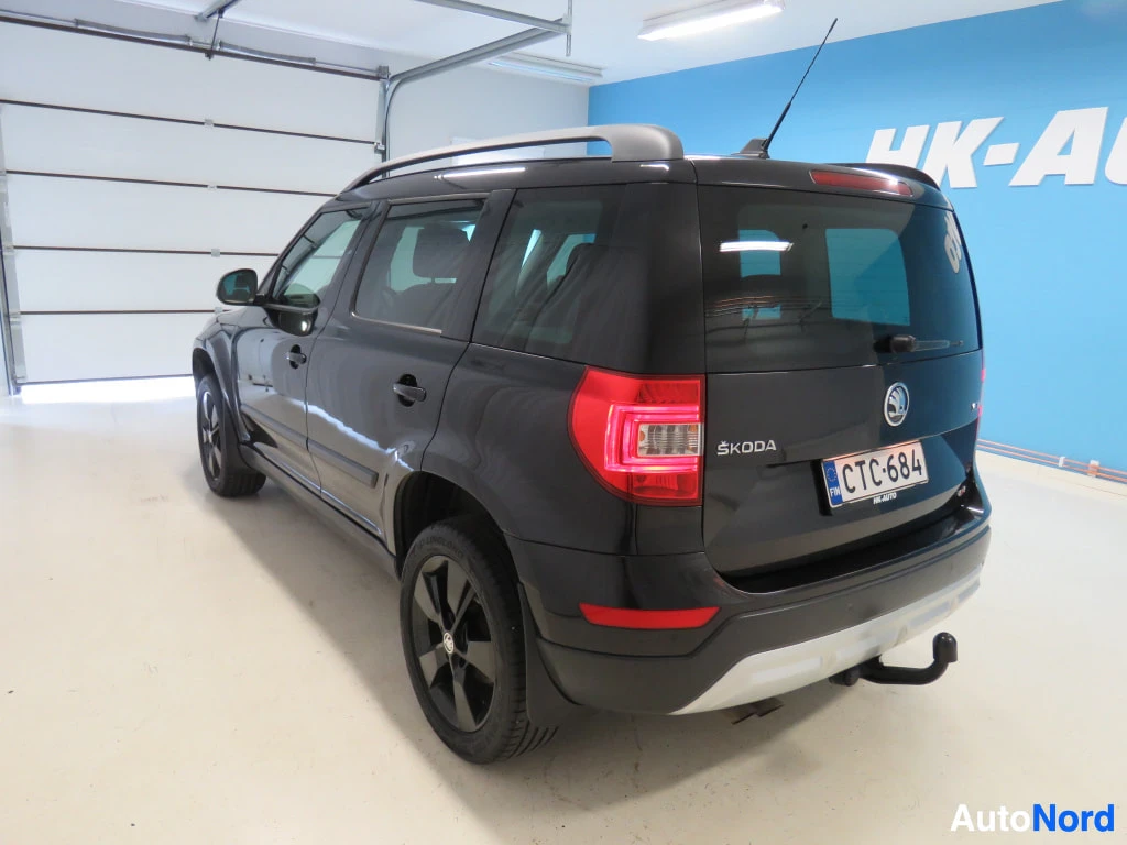 Takaviisto: Mustan farmariauton takakulma katetussa autotilassa; rekisterikilpi ja takavalot näkyvät.