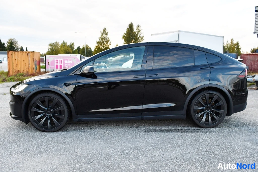 Etuviisto, nokka vasemmalle: Musta Tesla Model X -maasturin sivuprofiili vasemmalta; tummat monipuoliset vanteet ja tummat ikkunat.