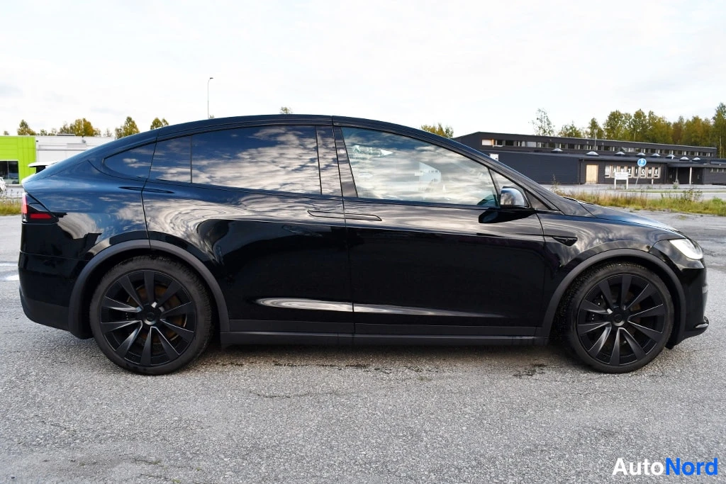 Sivulta: Mustan SUV-auton sivuprofiili vasemmalta kuvattuna, tummat vanteet, kirkas asfaltti.