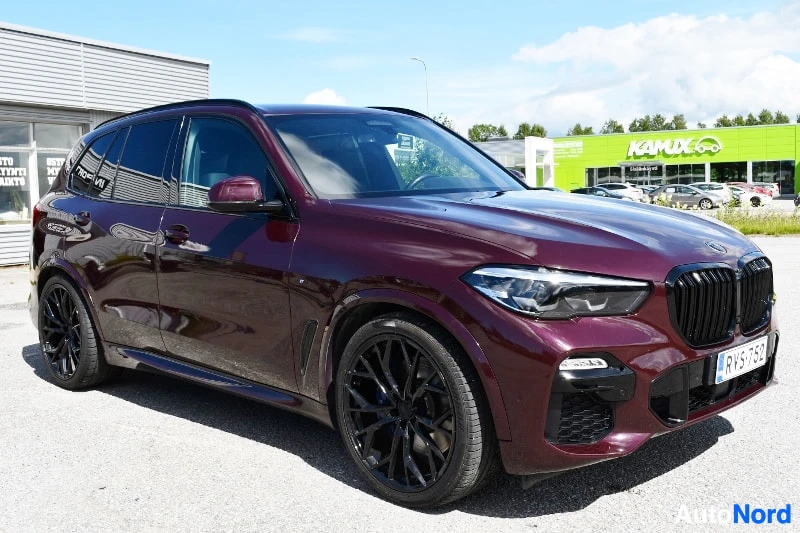 Etuviisto, nokka oikealle: Tummanpunainen BMW X5 etuoikealta kolmannenvälin kuvakulmasta mustilla vanteilla.