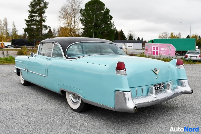 Takaviisto: Vaaleansininen klassinen coupe takaa oikealta, kromipuskurit ja rekisterikilpi, musta katto.