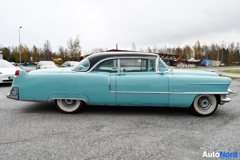 Sivulta: Vaaleansininen Cadillac Coupe Deville sivulta kuvattuna, musta katto ja whitewall-renkaat