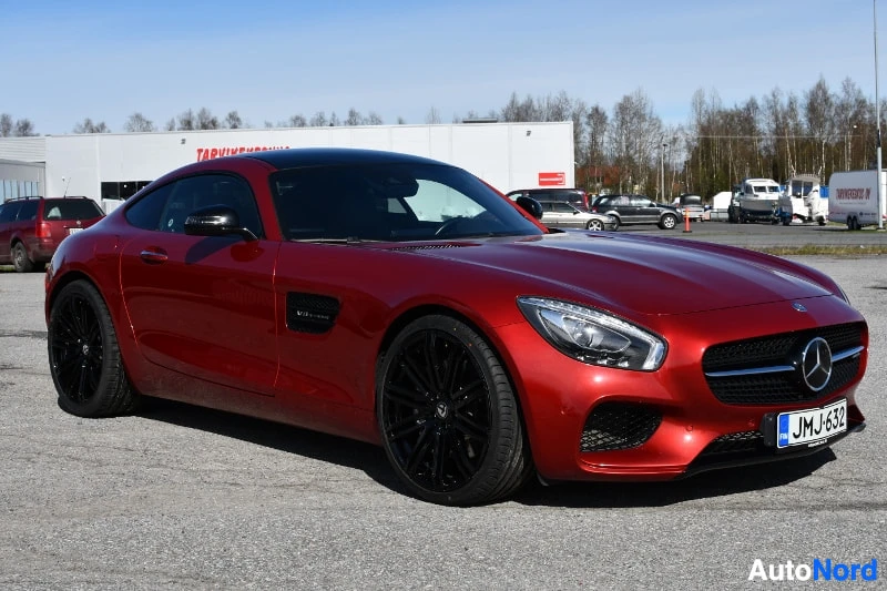 Etuviisto, nokka oikealle: Punainen Mercedes-Benz GT-coupé etuviistossa, tummat vanteet ja musta katto, kirkas aurinkoinen sää.