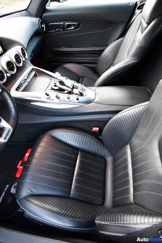 Etuistuimet: Musta nahkasisusta, urheiluistuimet, AMG-pohjamatot ja keskikonsolin kierrokviritys luija Mercedes-AMG GT:n etumatkustamossa.