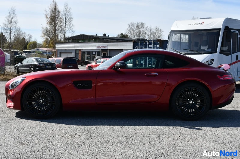 Etuviisto, nokka vasemmalle: Punainen Mercedes-AMG GT -coupé sivulta, keula vasemmalla, mustat vanteet ja takasiipi näkyvissä parkkipihalla.