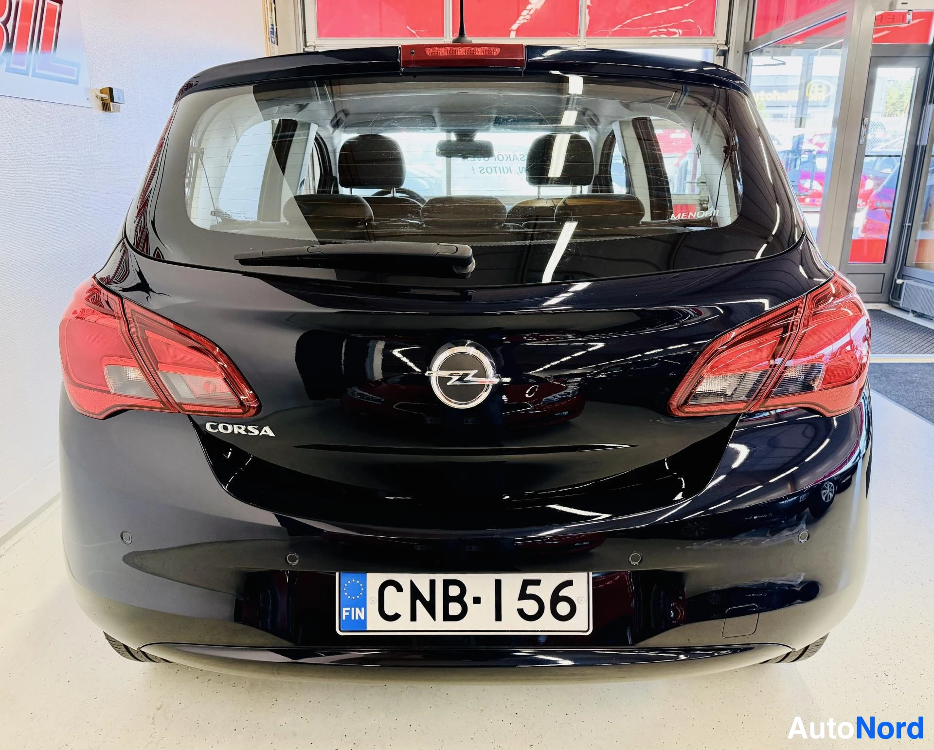 Takaa: Mustan sinertävän tumman Opel Corsa -auton takaosa suoraan edestä; korimerkki Corsa, Opel-logo, takavalojen korostus ja rekisterikilpi näkyvät.