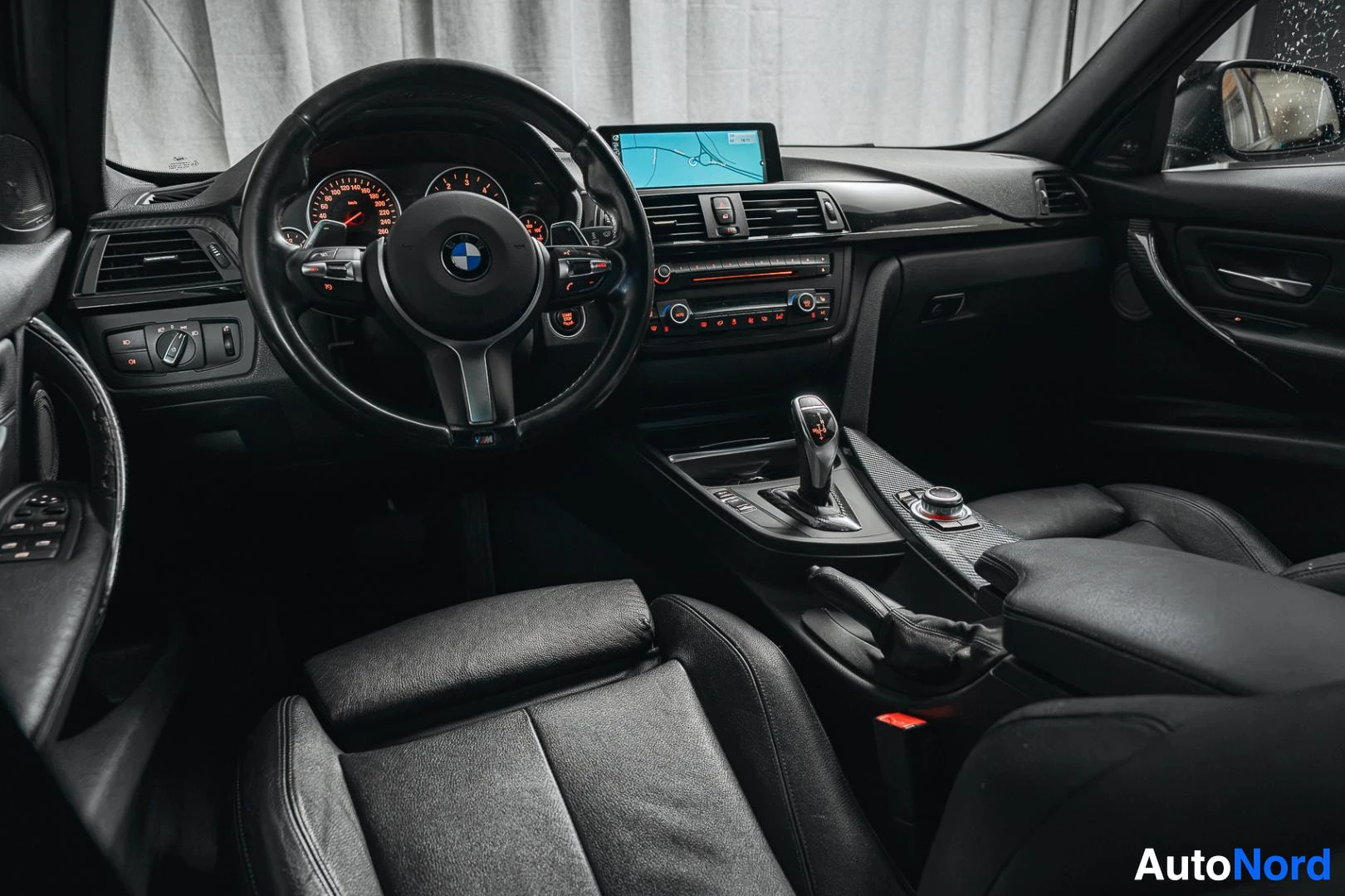 Etuistuimet: Ohjaamo vasemmalta ohjatulta: BMW-ohjauspyörä, mittaristo, navigointinäyttö ja automaattivaihteen valitsin.