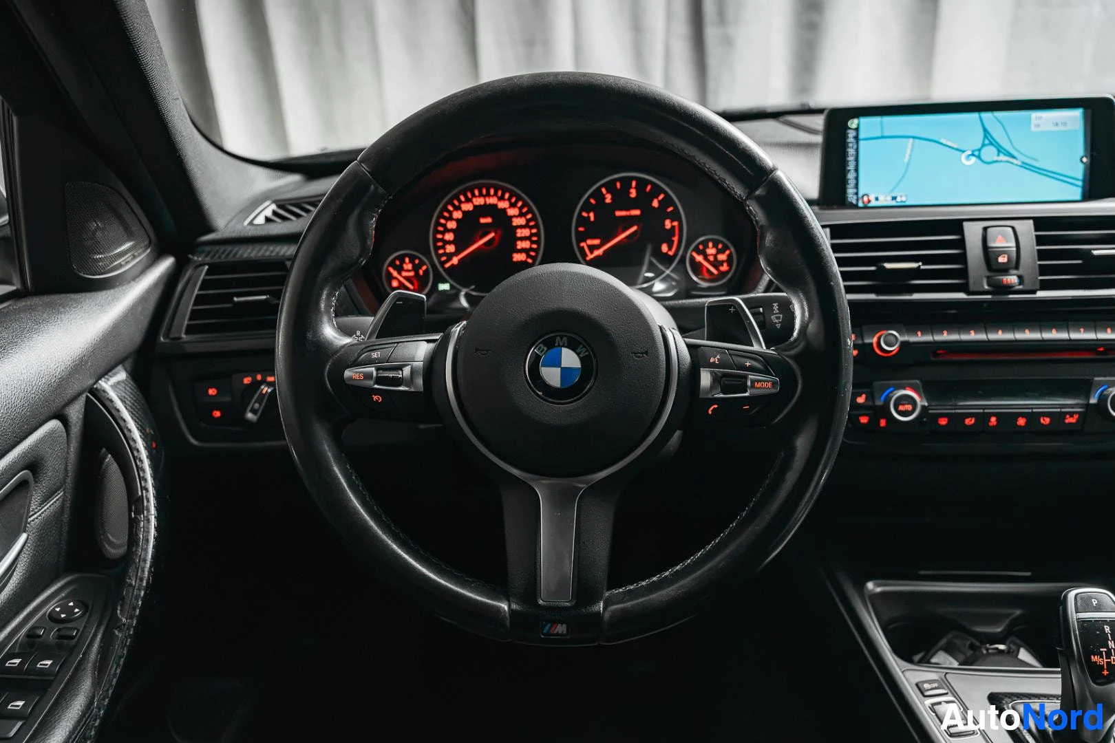 Muu: BMW-merkkinen M-urheiluohjauspyörä punavaloisilla mittareilla ja vaihdossaominaisuuslavalla, kojelaudassa karttanavigaationäyttö.
