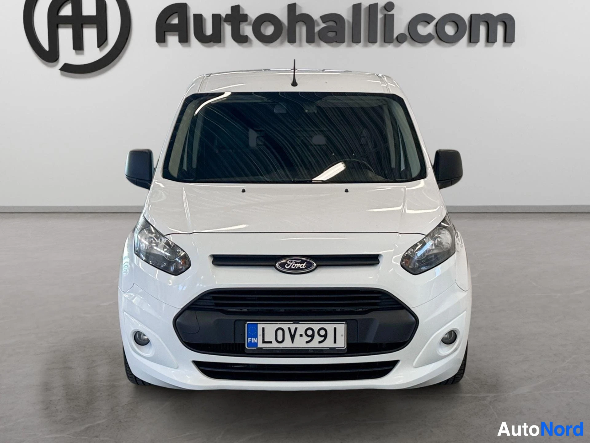 Edestä: Valkoisen Ford Transit Connectin etunäkymä, rekisterikilpi ja Ford-merkki näkyvissä.