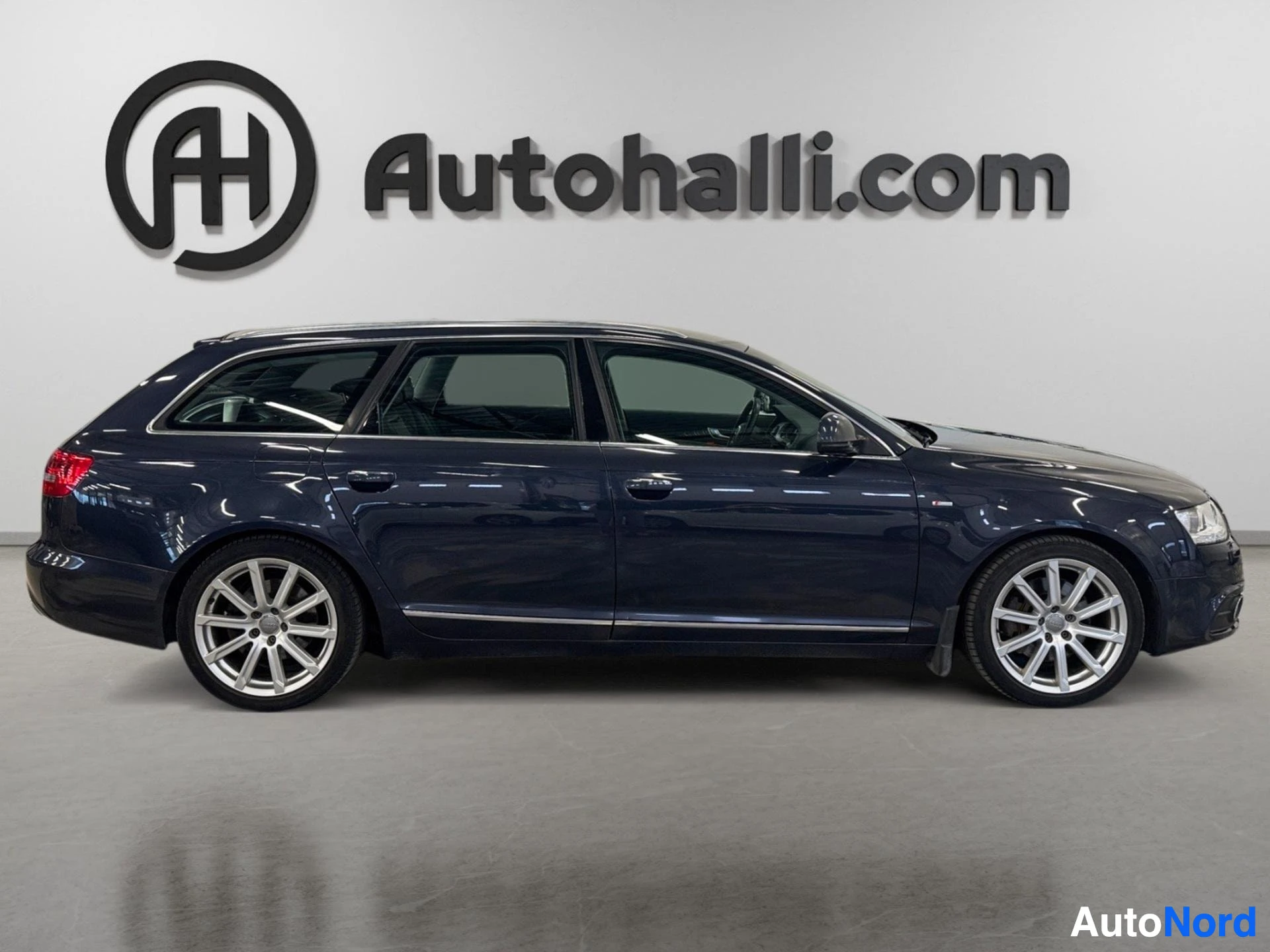 Sivulta: Tummansinisen Audi A6 Avantin sivukuva, hopeanväriset monipuoliset vanteet ja kromilista oven alareunassa.