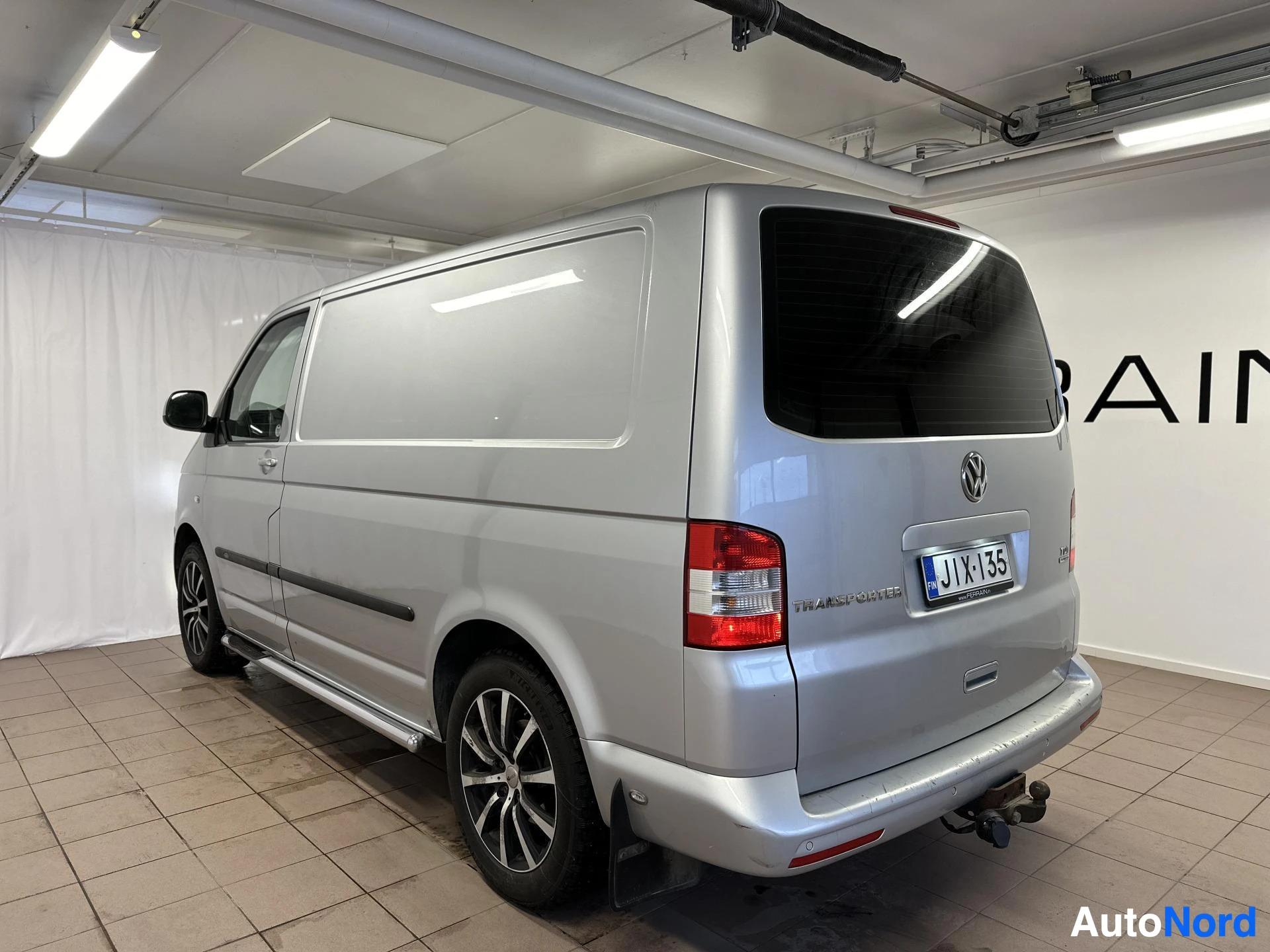 Takaviisto: Volkswagen Transporter -pakettiauto takakulmasta vasemmalta kuvattuna autotallissa.