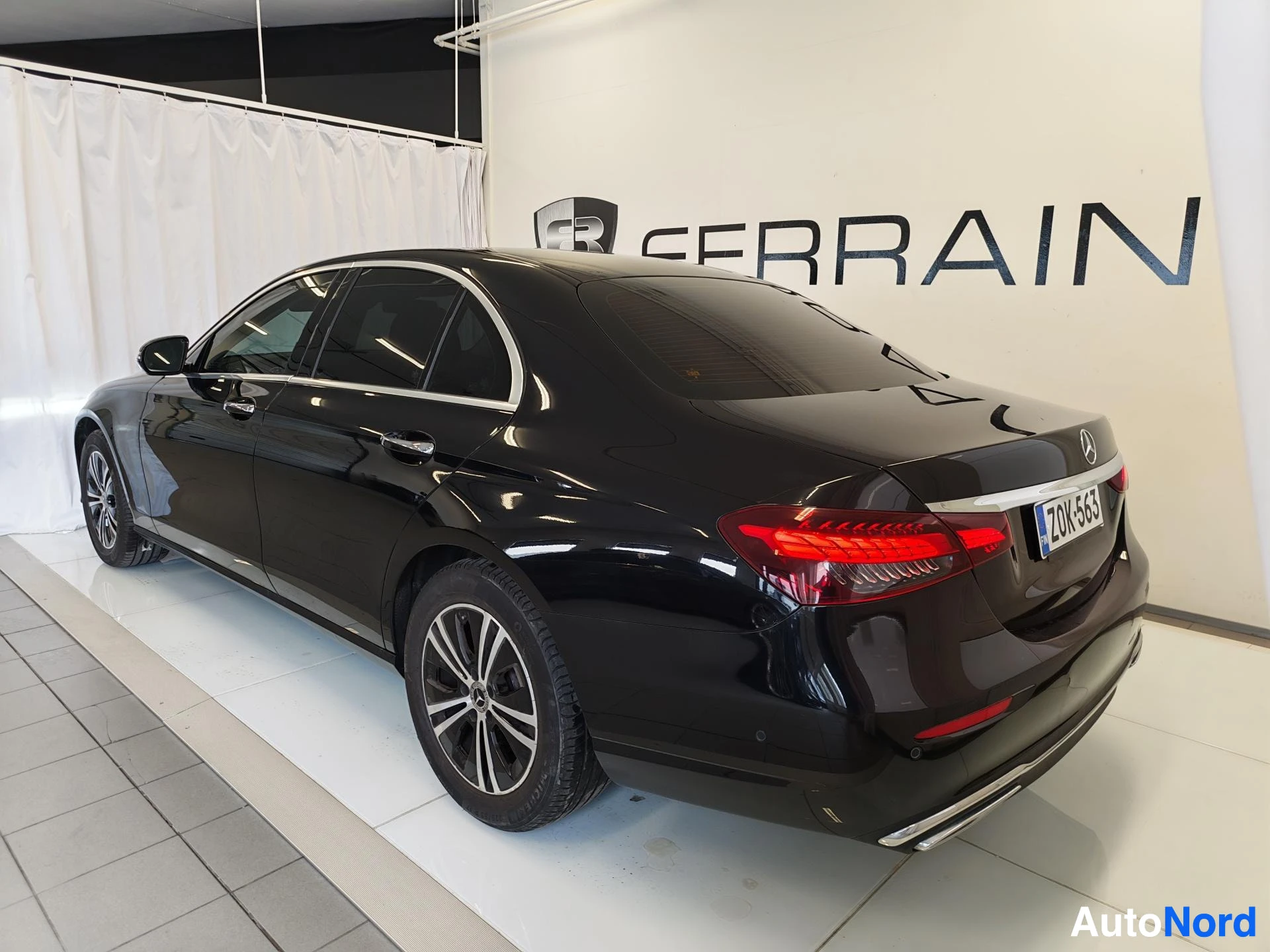 Takaviisto: Mustan Mercedes-Benz E-sarjan sedanin takapää ja punaiset takavalot, rekisterikilpi.